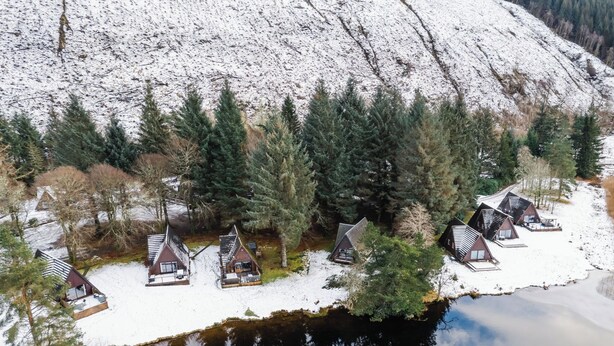 A lakeside cabin area with several cabins, a dock, and a snowy landscape. - Invergarry Combi by Interhome (Invergarry)