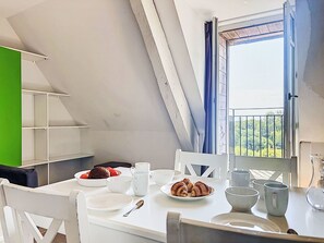 A dining area with a table set for breakfast, including croissants and fruit, and a view of greenery outside. - Le Château de Kergonano by Interhome (Baden)