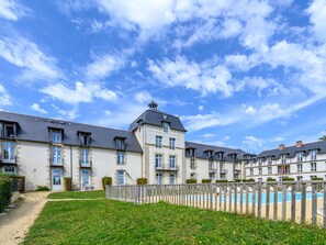 A row of multi-story buildings with a swimming pool in the foreground. - Le Château de Kergonano by Interhome (Baden)