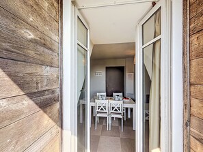 An open doorway leading to a dining area with a table and chairs, a dark door, and a small wall-mounted sign. - Le Château de Kergonano by Interhome (Baden)