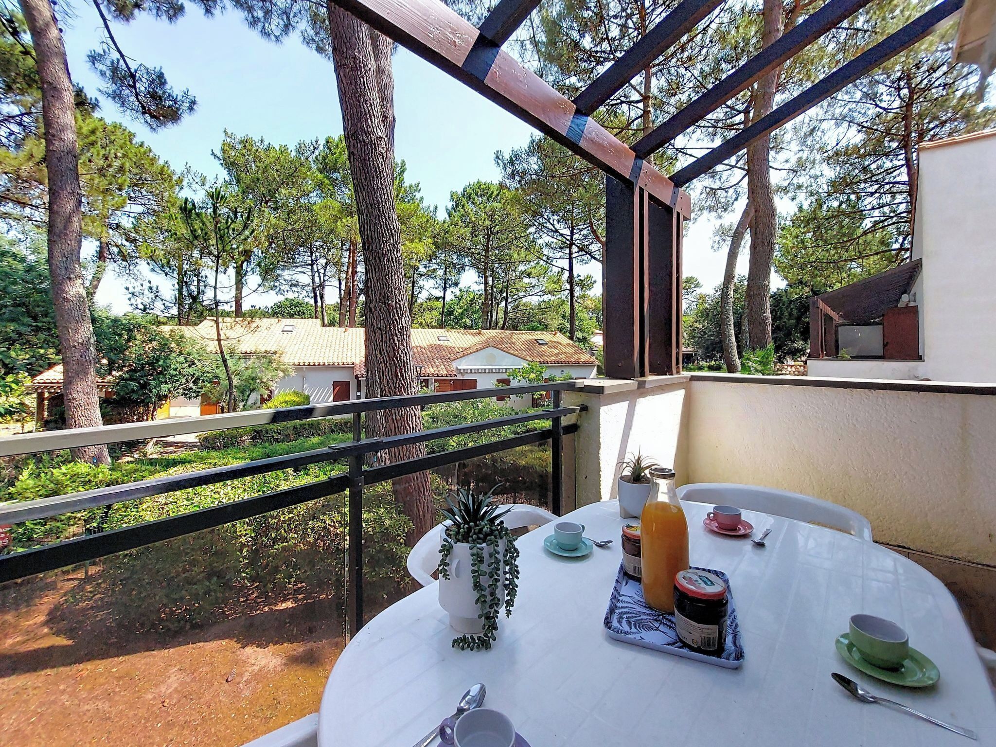 Un balcó amb taula preparat per esmorzar, amb vista a una zona boscosa.