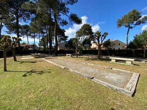 A courtyard with a bocce court, benches, and surrounding trees. - Hameau de Talaris by Interhome (Les Mathes)