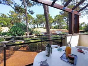 A balcony with a table set for breakfast, overlooking a garden and houses. - Hameau de Talaris by Interhome (Les Mathes)