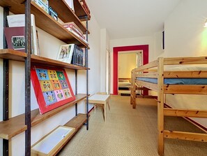 A room with bunk beds, a bookshelf with books and a framed artwork, and a small table. - Villa Piscine - Aigues-Vives by Interhome (Aigues-Vives)