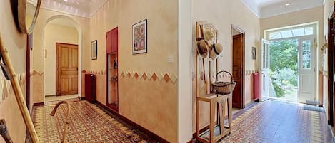 A hallway with patterned tiles, wooden doors, and a large mirror.
