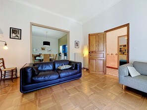 A living room with a blue leather sofa, a grey sofa, wooden flooring, a wooden door, and a dining area in the background. - Villa Piscine - Aigues-Vives by Interhome (Aigues-Vives)