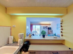 A compact kitchen with a view of the balcony, a Bosch coffee maker, a sink, and a countertop. - Lydia Playa by Interhome (Le Barcarès)