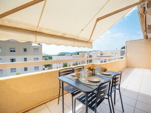 A balcony with a table set for two, a chair, and a view of the cityscape. - Santa Barbara by Interhome (Cavalaire)