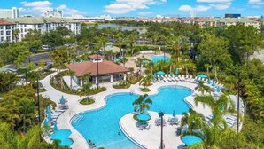 Un resort con múltiples piscinas, palmeras y vistas al horizonte de la ciudad.