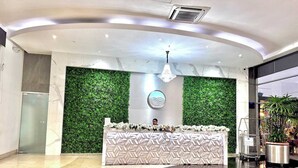 A reception desk with a geometric patterned backdrop, a modern chandelier, and a green wall.