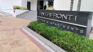 A sign for Riverfront I Suites & Apartments with a modern entrance and steps leading up to the building.