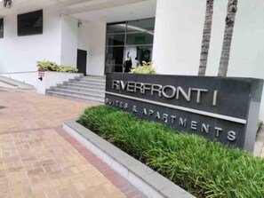A sign for Riverfront I Suites & Apartments with a modern entrance and steps leading up to the building.