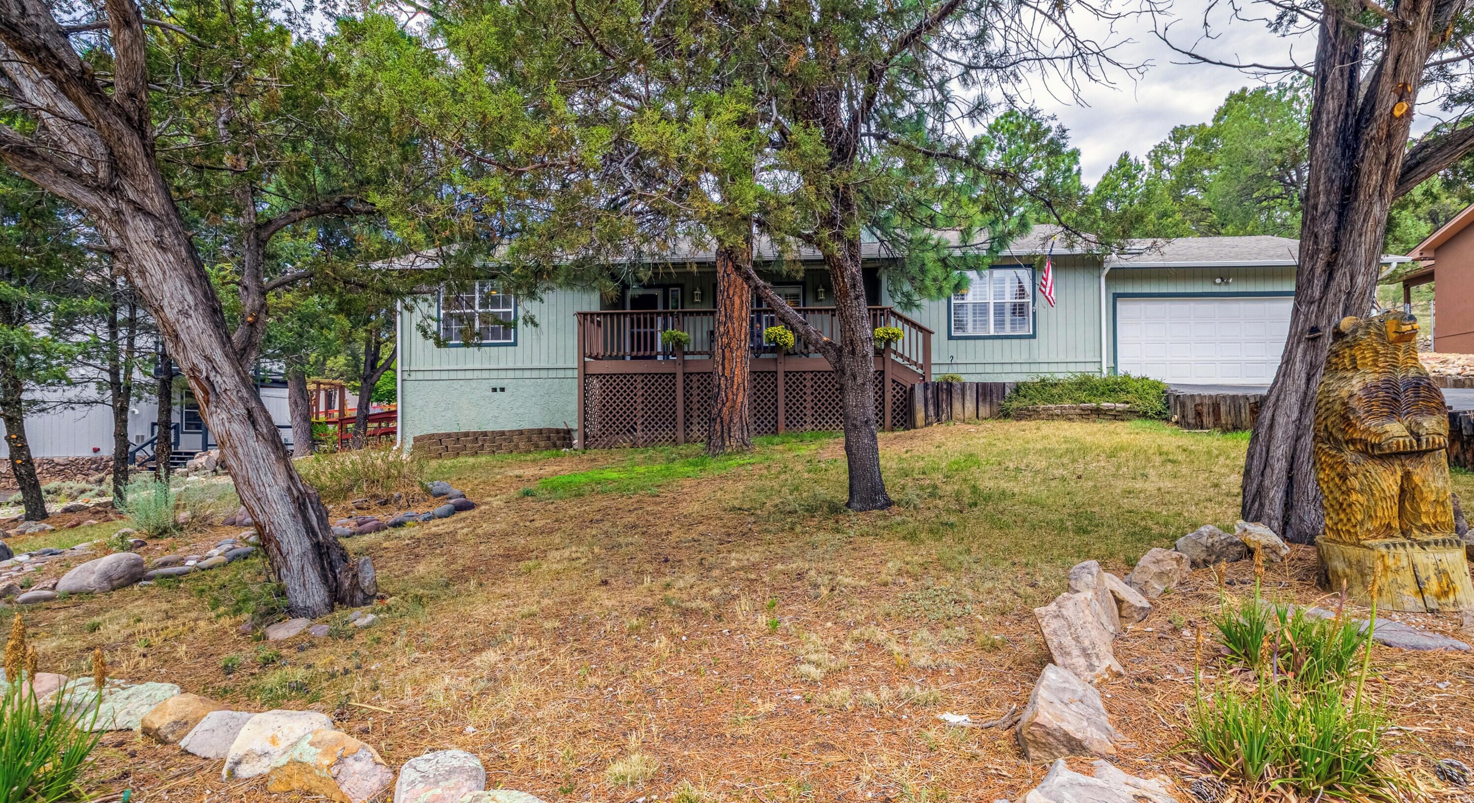 A residential property with a house, a covered porch, and a front yard with rocks and sparse grass.