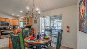 A modern kitchen with wooden cabinets, a stainless steel microwave, and a dining area with a round table set for four. - Lazy D Cabin: Inspired by a West Texas ranch. Built for mountain memories. (Ruidoso)