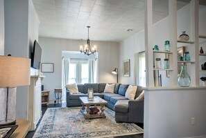 Ein Wohnzimmer mit Ecksofa, Couchtisch, einer Deckenleuchte und einem Teppich.