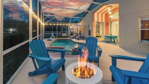 Eine Terrassenausstattung im Freien mit Feuerstelle, blauen Adirondack-Stühlen und einem Pool.
