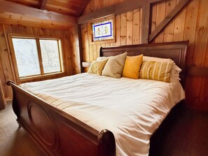Ein Schlafzimmer mit Holzwänden, einem Bett und einem Buntglasfenster.