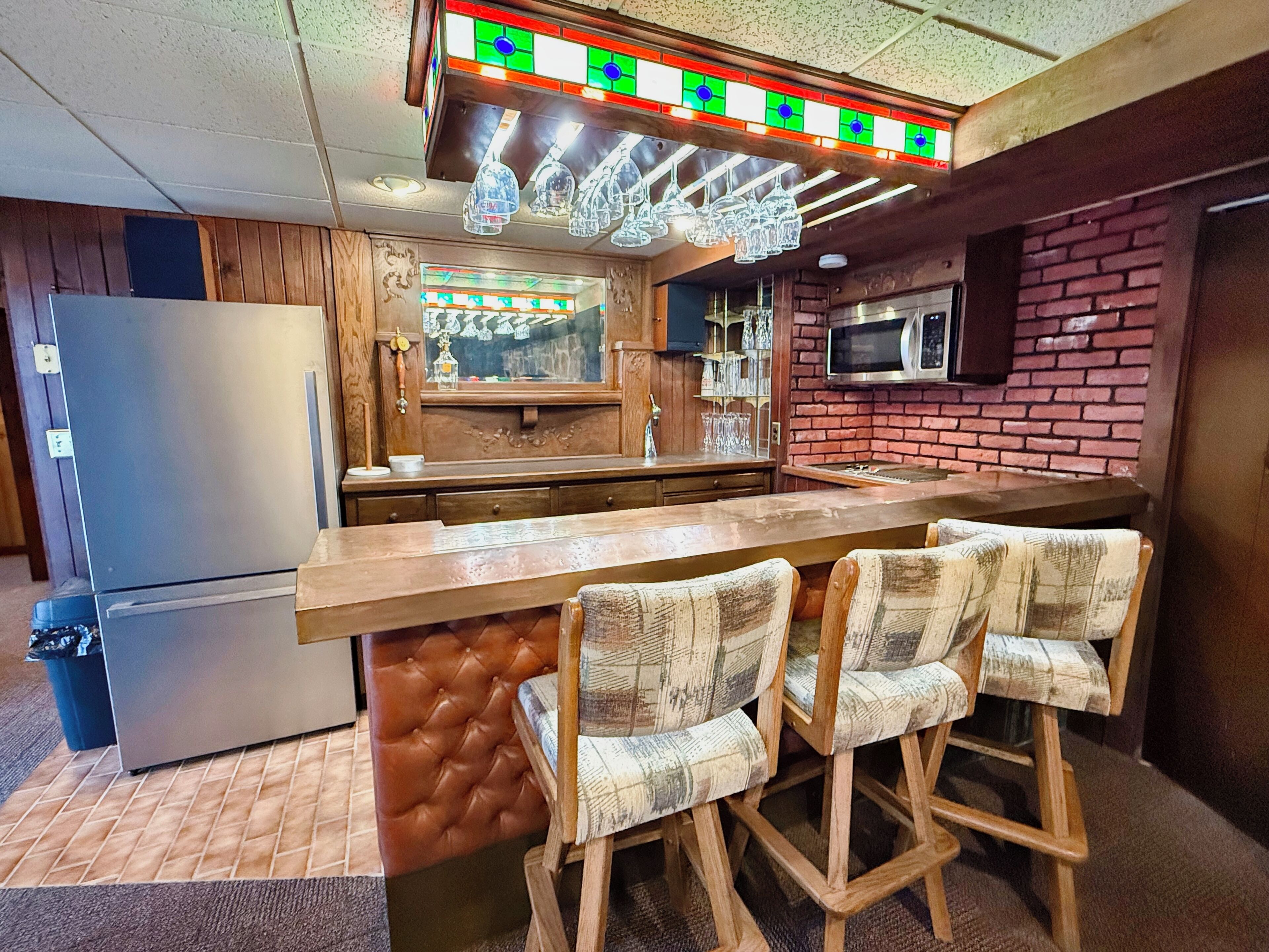 Une cuisine équipée d’un bar en bois, de tabourets de bar, d’un réfrigérateur et d’un four à micro-ondes.