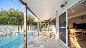 Ein überdachter Außenbereich mit Pool, Terrassenmöbeln und Blick ins Hausinnere.