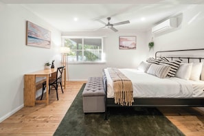 A bedroom with a bed, a desk, a chair, a ceiling fan, and a window with blinds. - Caloundra Tropical Downstairs Stay – Pool & Garden (Caloundra Region)