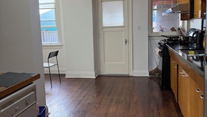 Una cocina con suelo de madera, estufa, armarios y ventana con vistas a un balcón.