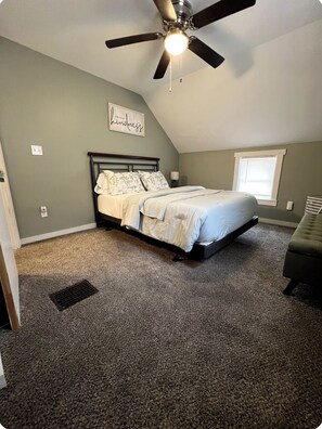 A bedroom with a bed, a ceiling fan, a window, and a wall with a sign. - Welcome to Red and Ready! Pet Friendly. AC's in both bedrooms for comfort. (Springfield)