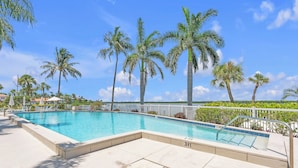 Une piscine dont la profondeur maximale est de 3 pieds, entourée de palmiers et surplombée d’un ciel bleu azur.