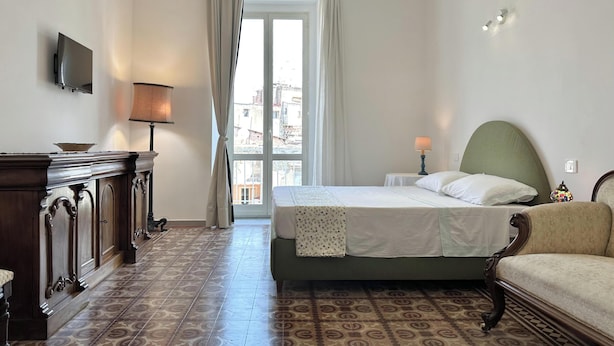 Et hotelværelse med seng, sofa, fjernsyn, lampe, bord og udsigt ud.