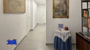 En gang med kunstværker, et bord med en bog og en bogreol.