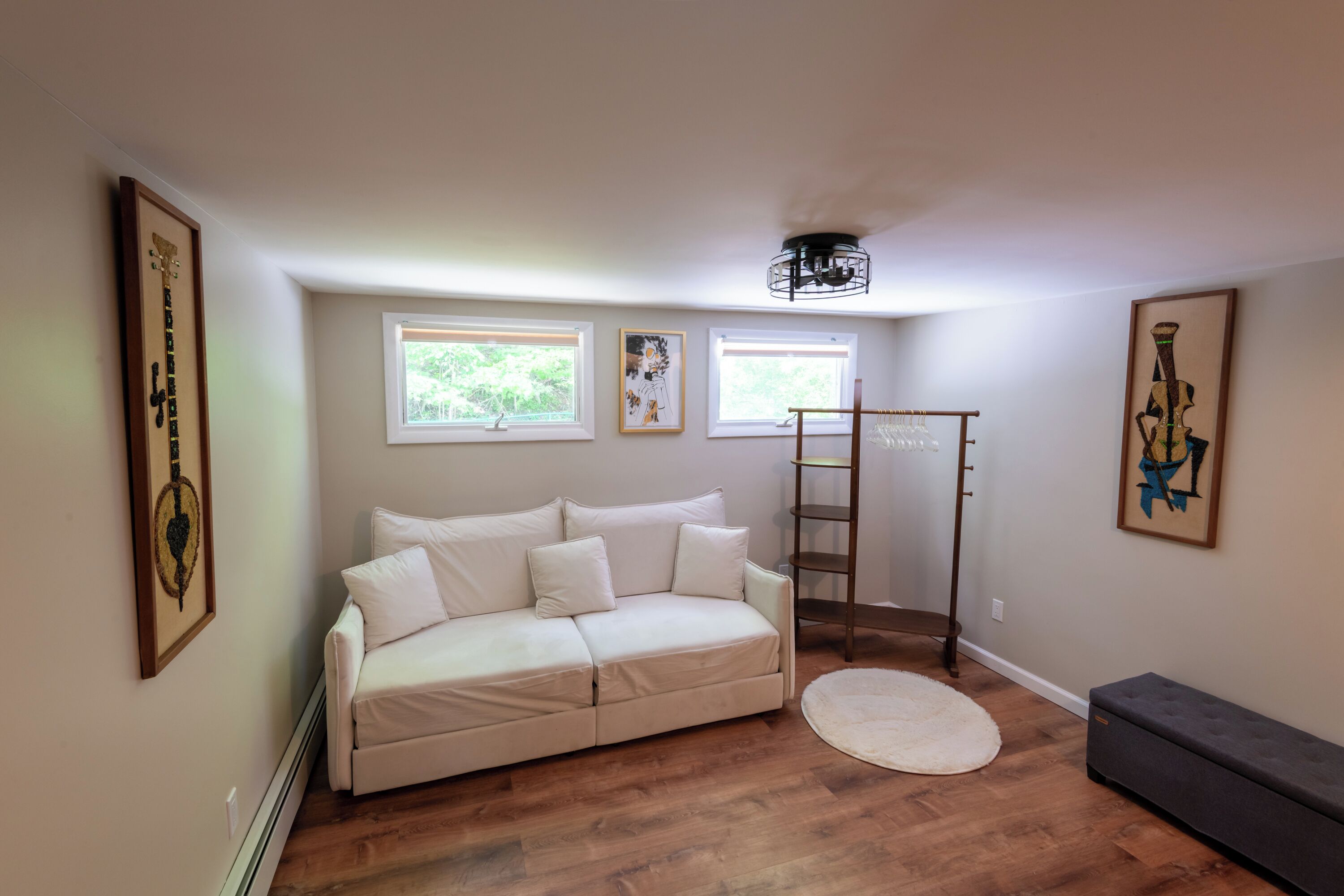 A room with a white sofa, a small round rug, a bench, and a ladder against the wall.