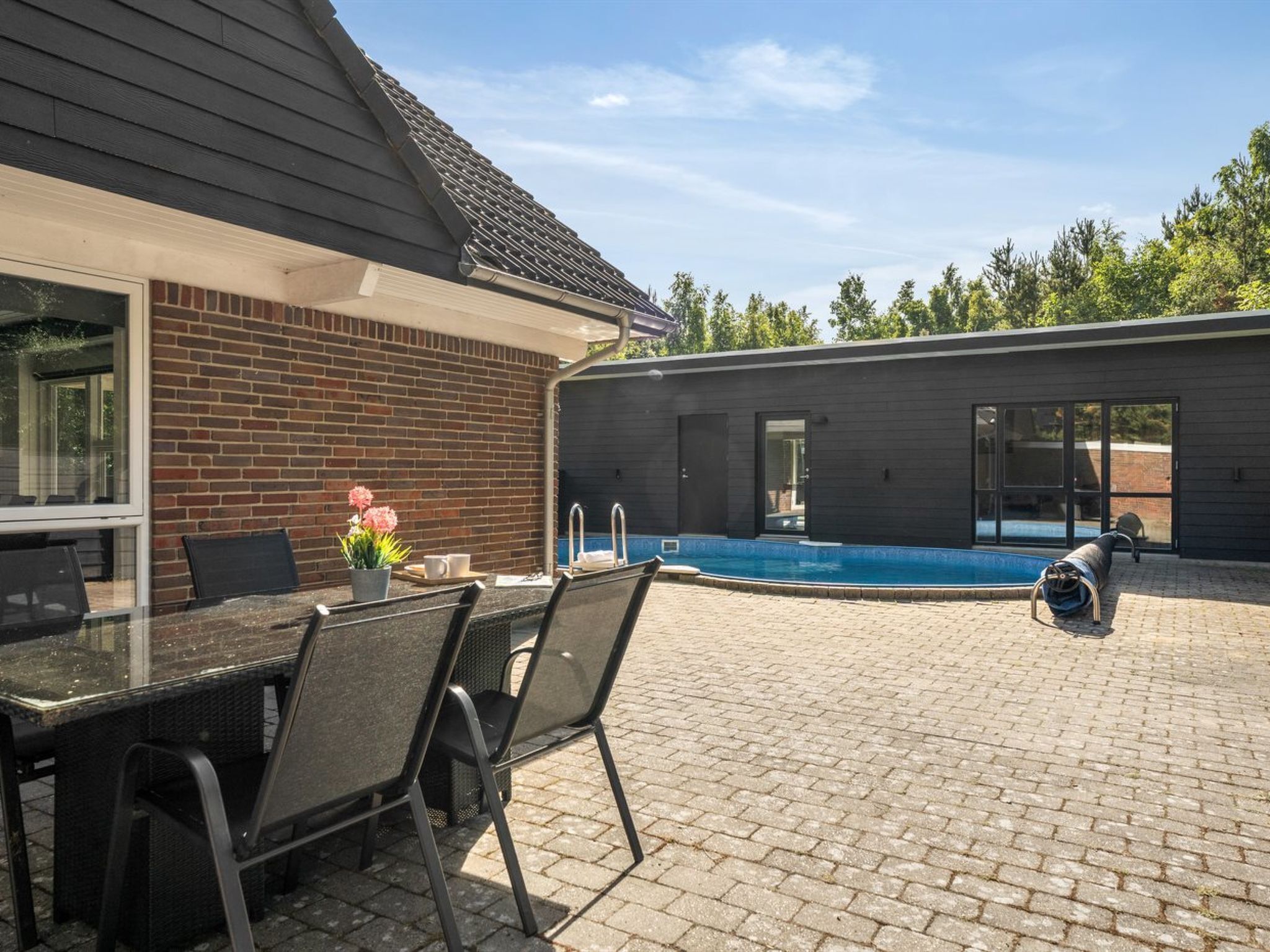 A patio with a pool, outdoor seating, and a modern building with large windows.