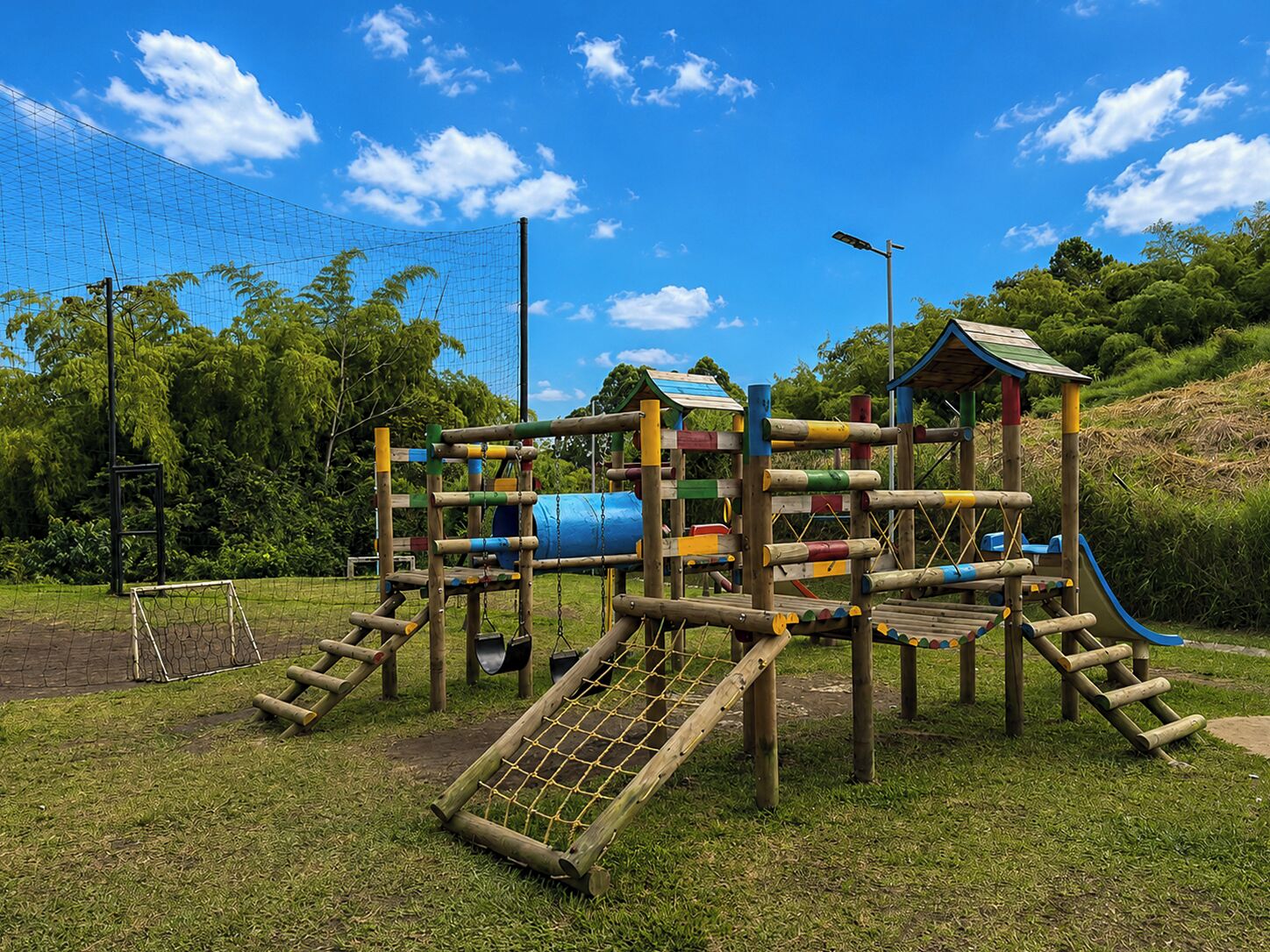 A playground with a slide, climbing structures, and a netted area.