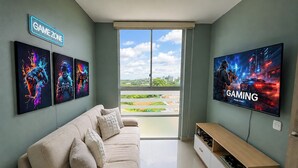Un salon avec un canapé, un téléviseur et des œuvres d’art accrochées au mur.