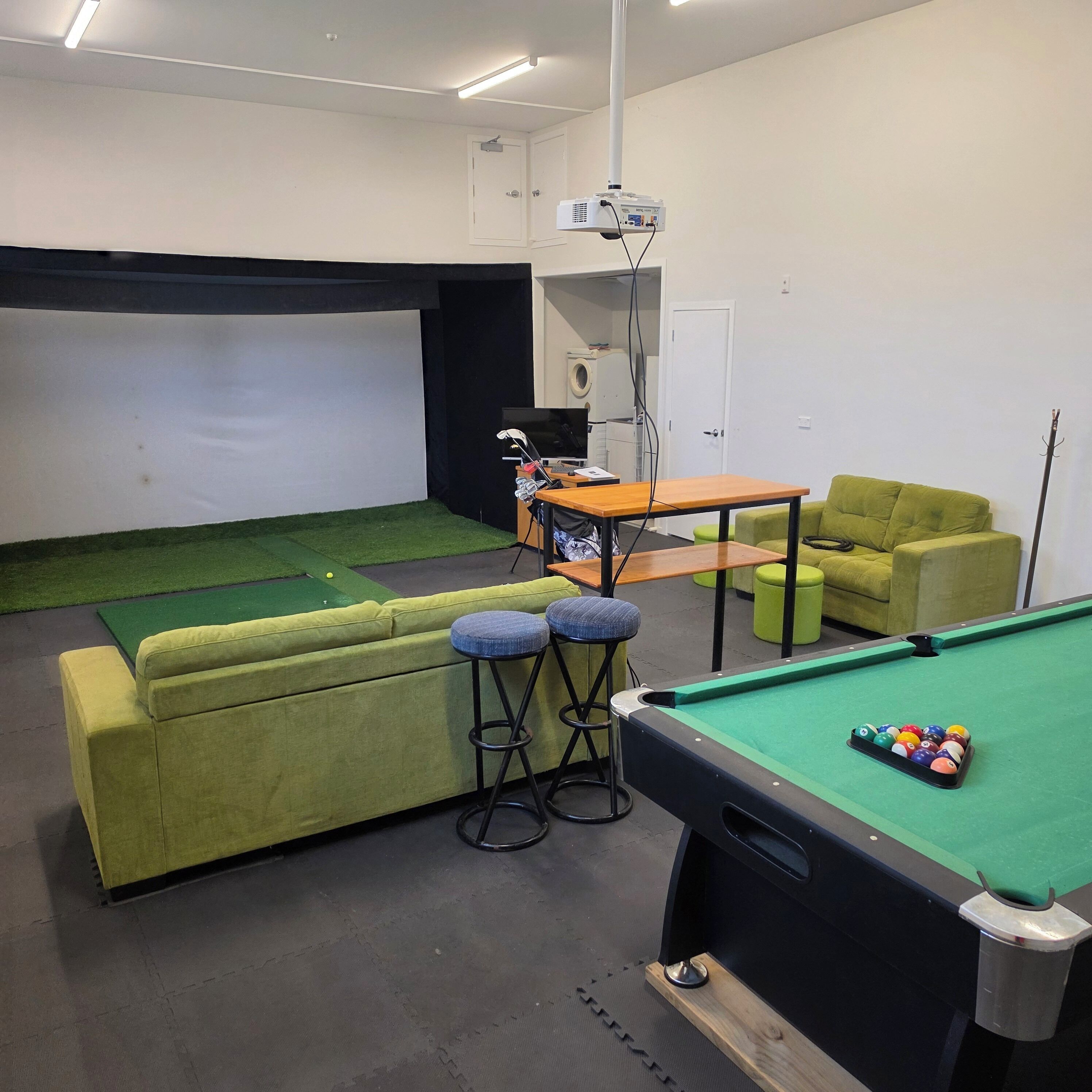 A pool table with balls, a projector, a sofa, and a small table with a television.