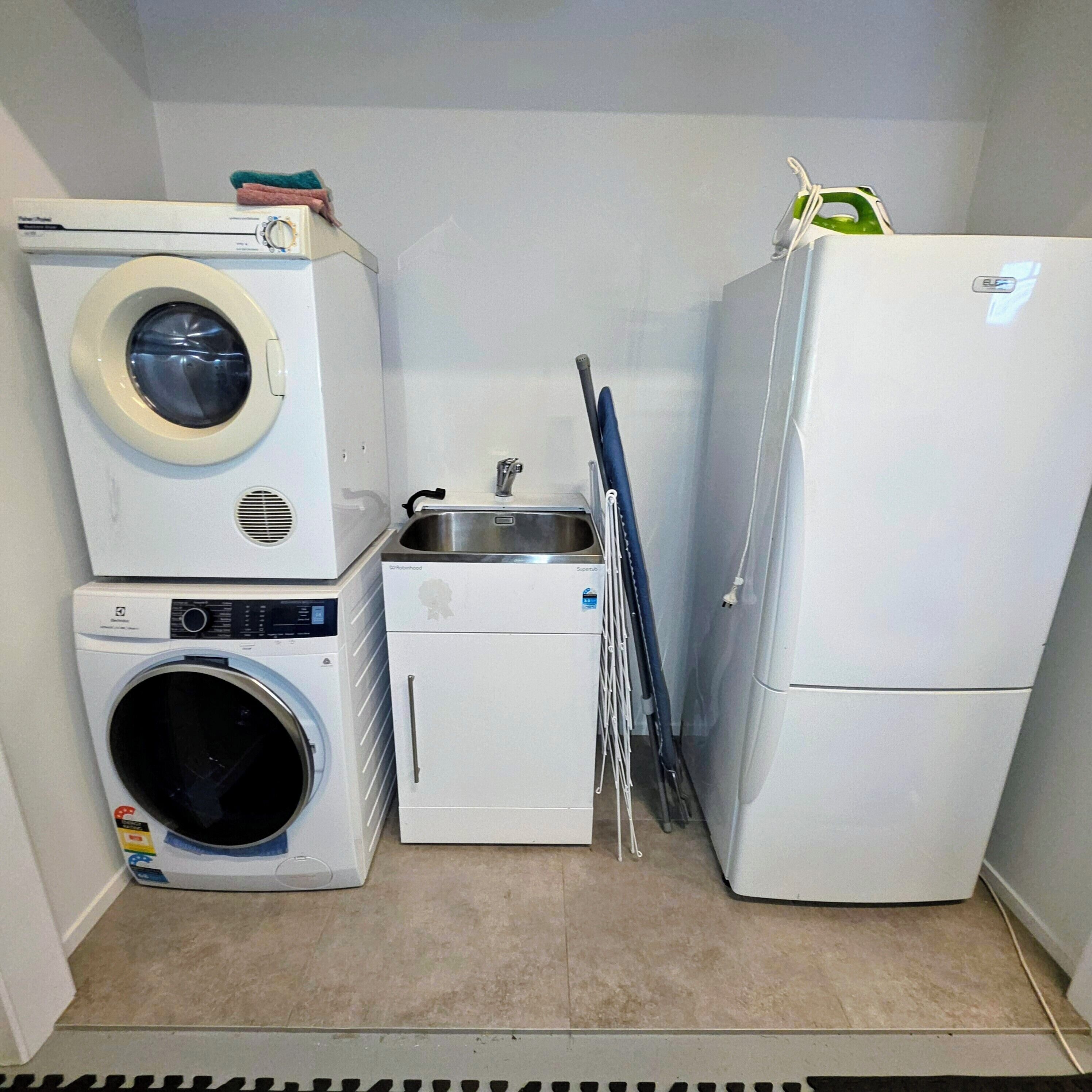 Une petite buanderie équipée d’un lave-linge, d’un sèche-linge et d’un réfrigérateur.