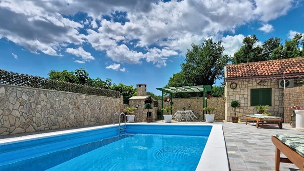 A swimming pool with a stone wall, a pergola, and outdoor furniture. - Vacation home Denis by Interhome (Benkovac)