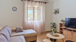A living room with a sofa, a TV, a small table, and a potted plant. - Vacation home Denis by Interhome (Benkovac)