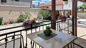 A covered outdoor area with a table and chairs, potted plants, and a stone wall. - Vacation home Denis by Interhome (Benkovac)