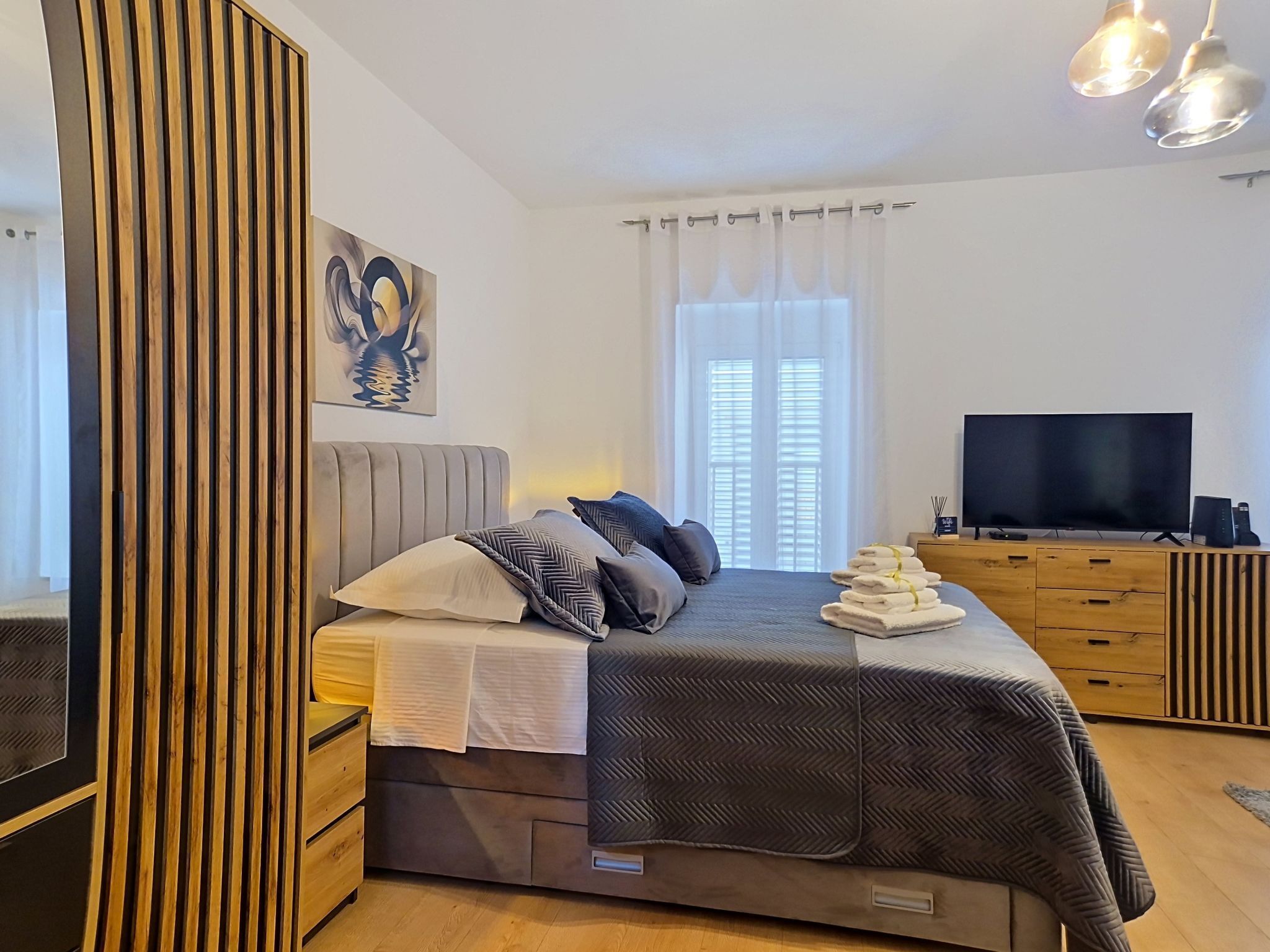 Une chambre moderne avec un lit, une télévision et une armoire en bois.