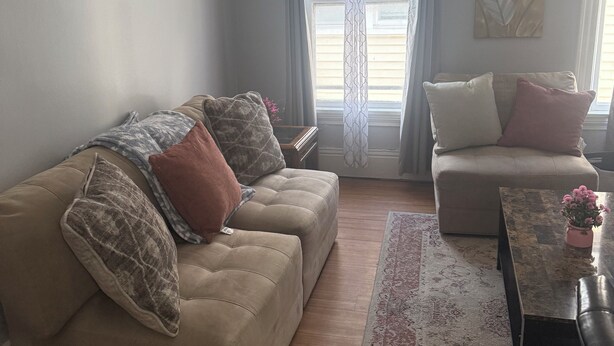 A living room with a beige sofa, a smaller couch, a coffee table, and a ceiling fan.