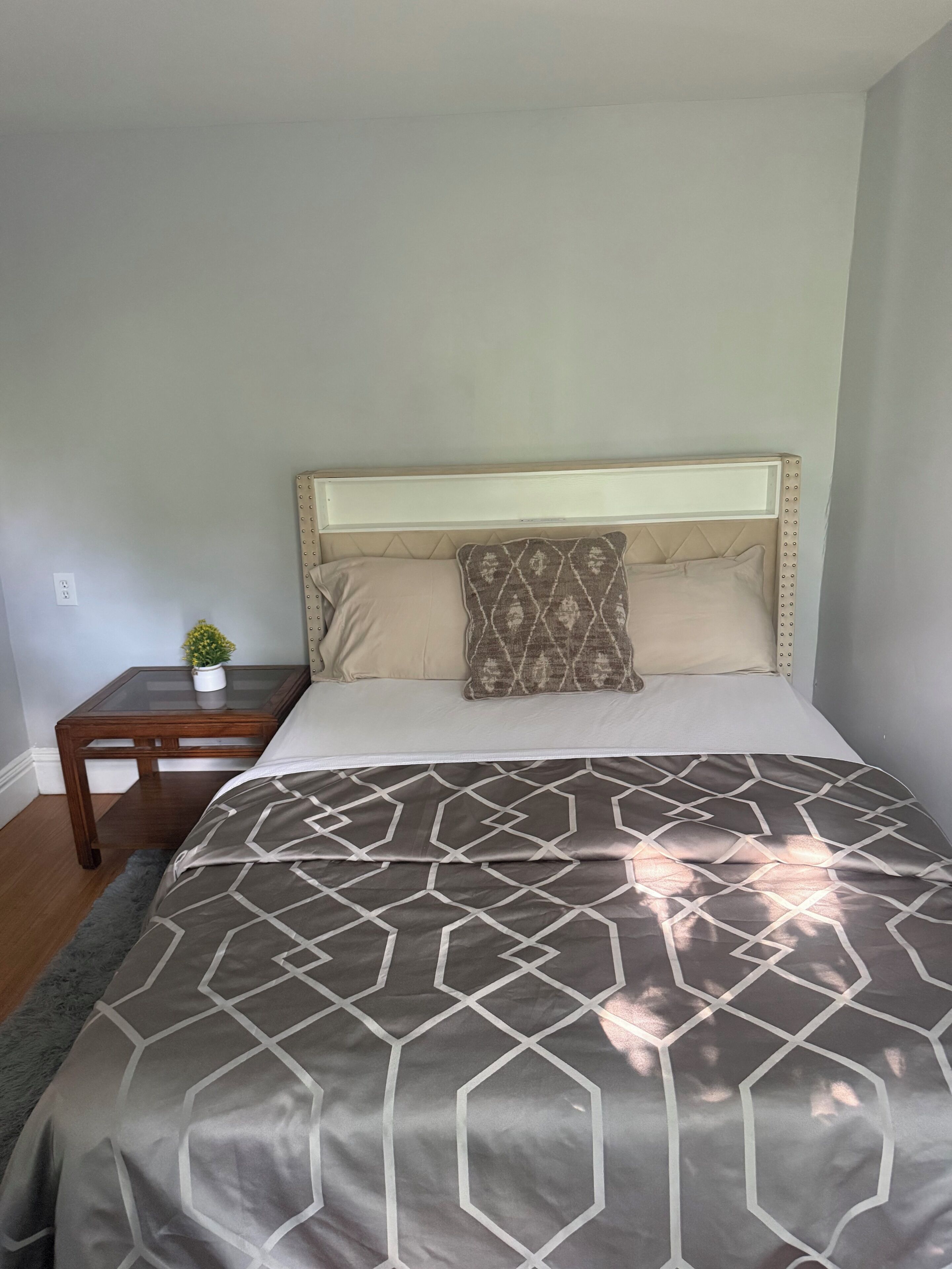 A bedroom with a bed, a nightstand, and a small potted plant.
