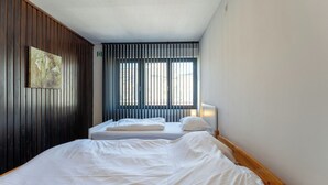 Una camera da letto con un letto grande, un letto più piccolo, una finestra con tende e un quadro appeso al muro.