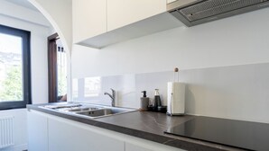 Una cucina moderna con piano di lavoro in marmo, lavello in acciaio inossidabile e cappa aspirante integrata.