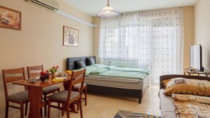 Een slaapkamer met een bed, een bureau met stoelen, een televisie en een raam met gordijnen.