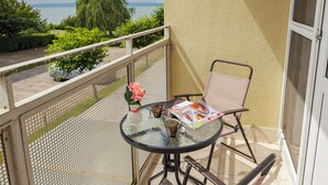 Een balkon met een tafel, stoel en een vaas met bloemen.