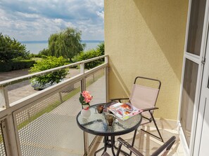Ein Balkon mit Tisch, Stuhl und Blumen in einer Vase.