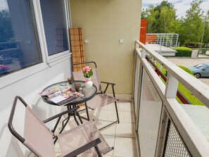 Ein Balkon mit Tisch, Stühlen, einer Blumenvase und Blick auf die Straße.