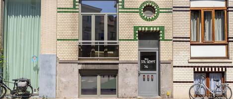 A building with a green awning, a bicycle parked outside, and a sign reading 'Villa Stil Genot 36'.