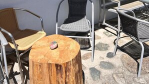 An outdoor seating area with wicker chairs and a wooden stump table, a window with a view of trees, and a yellow ceiling. - Solaria 31 Ferienhaus, Dusche oder Bad, WC 5 1/2- Ferienhaus by Interhome (Davos)