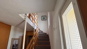 A staircase with wooden railings leading to an upper floor, a framed picture on the wall, and a window with blinds. - Solaria 31 Ferienhaus, Dusche oder Bad, WC 5 1/2- Ferienhaus by Interhome (Davos)